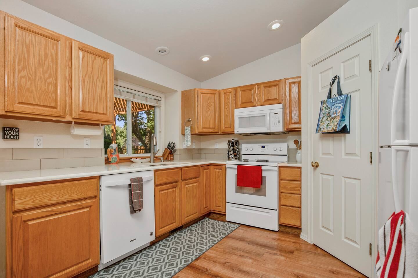 Kitchen with oak cabinets, white appliances and a window over the sink