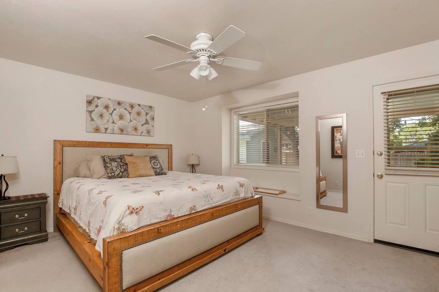 Primary bedroom with a king bed, ceiling fan and outside door
