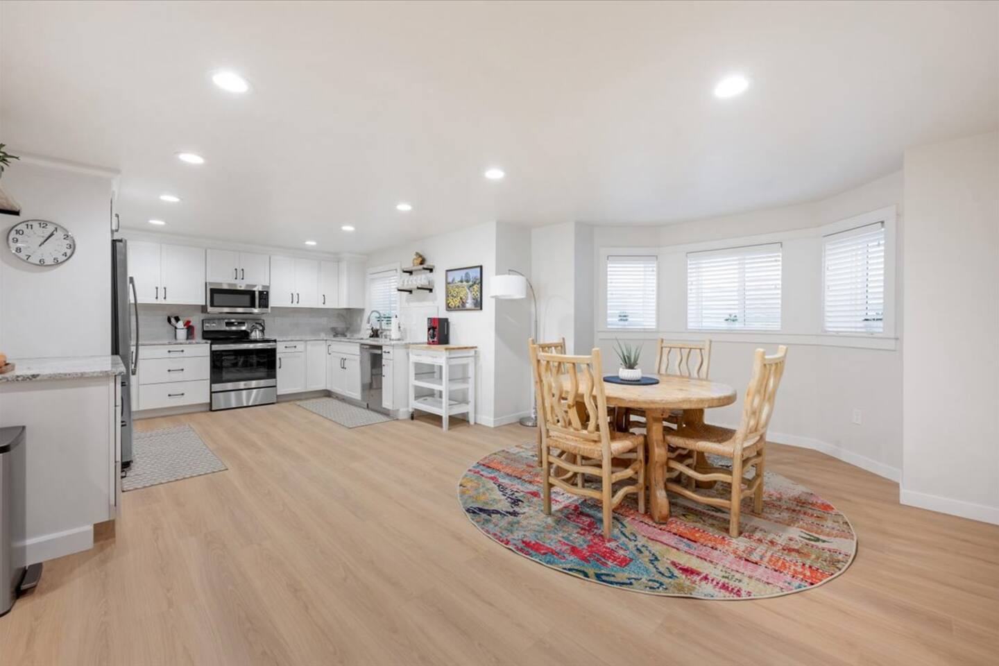Open kitchen with white cabinets, stainless appliances and a round dining table