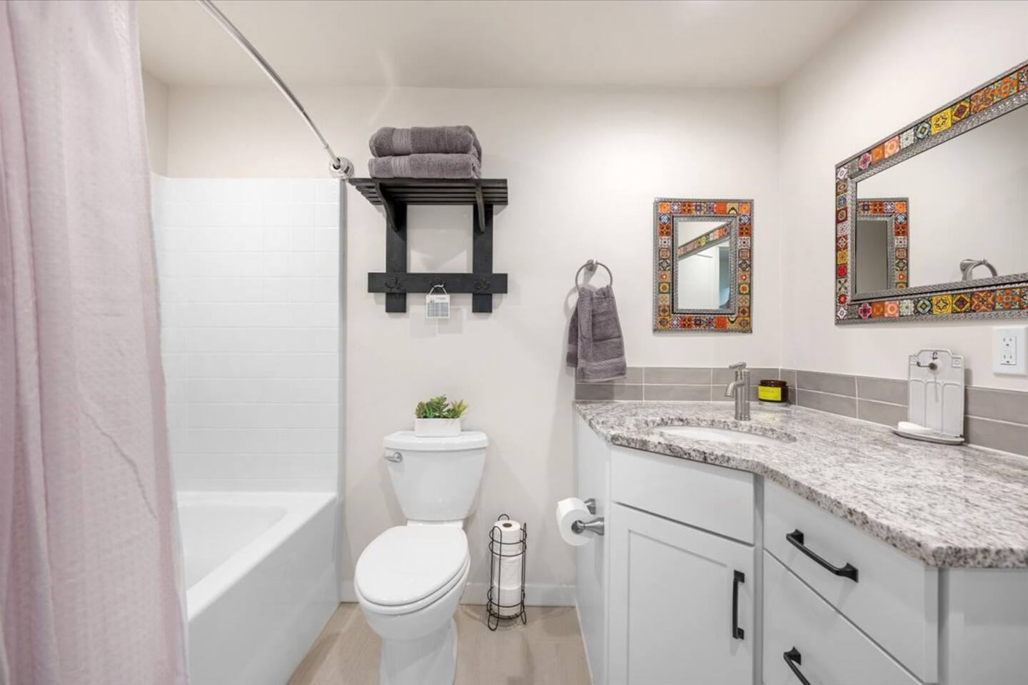 Full bathroom with tub, granite vanity and tiled mirror