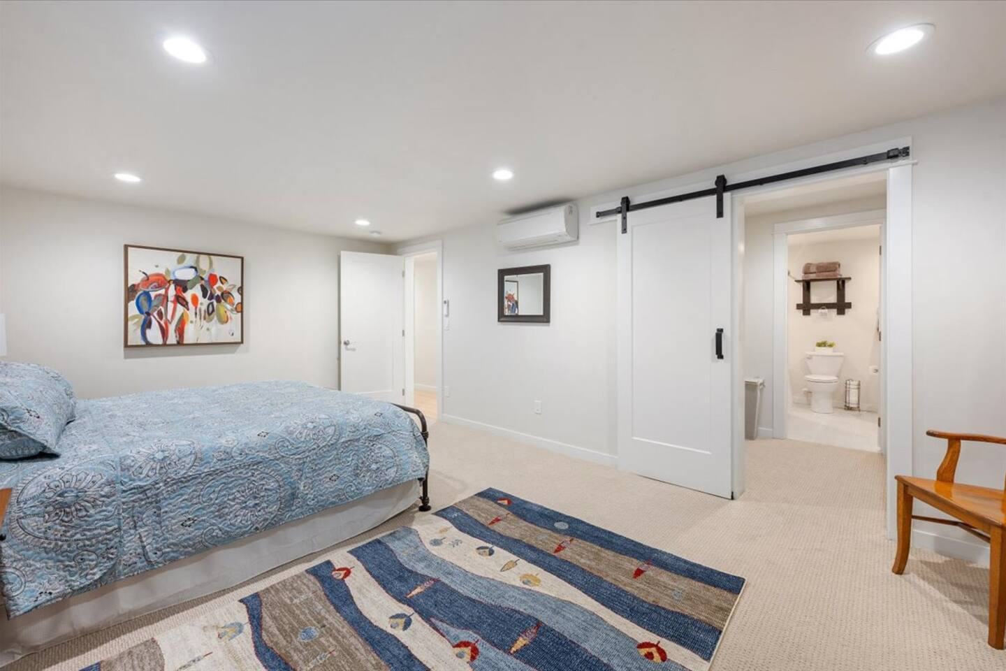 Large bedroom with a barn-door walk-in closet leading to a bathroom