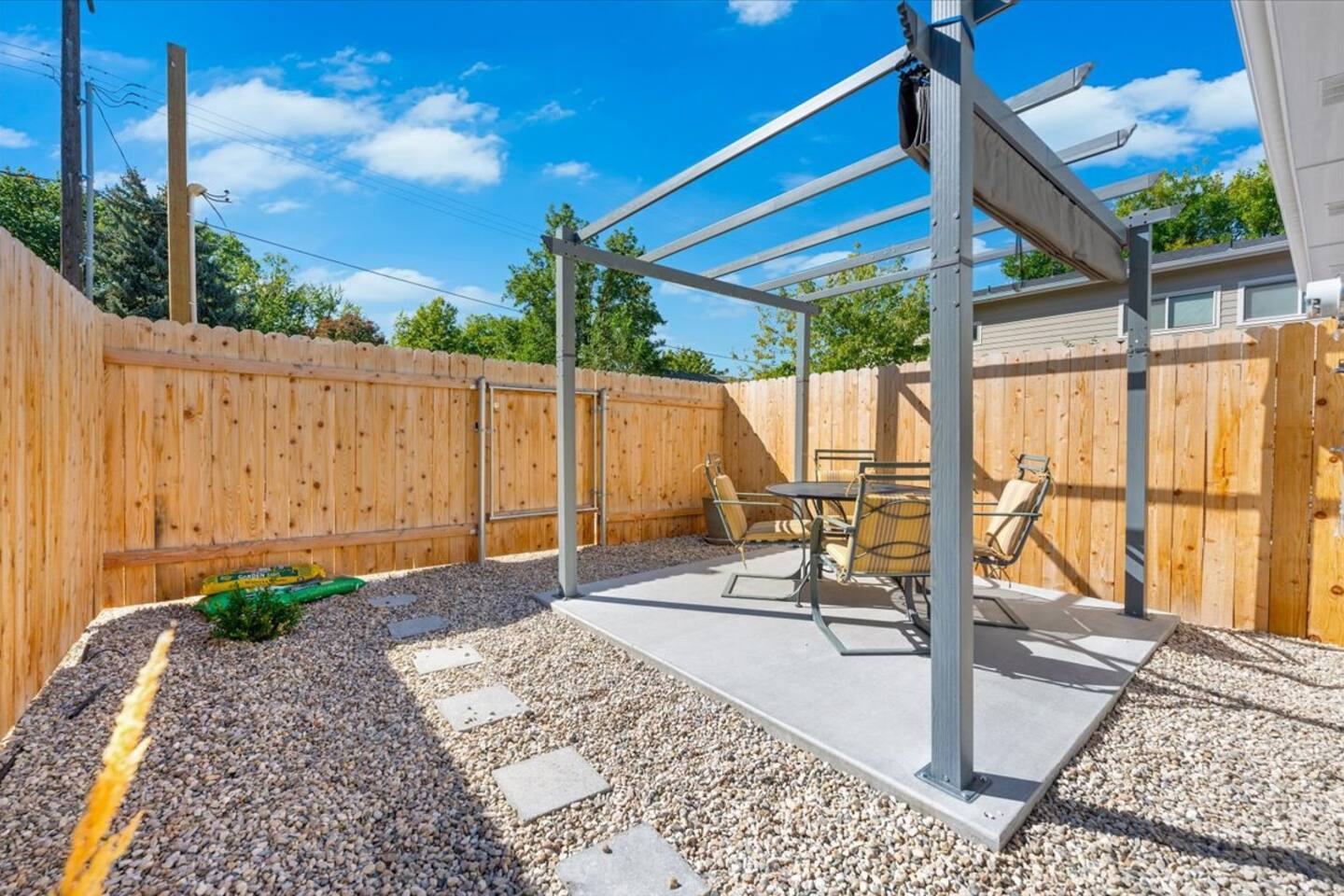 Fenced back patio with a pergola and outdoor dining set