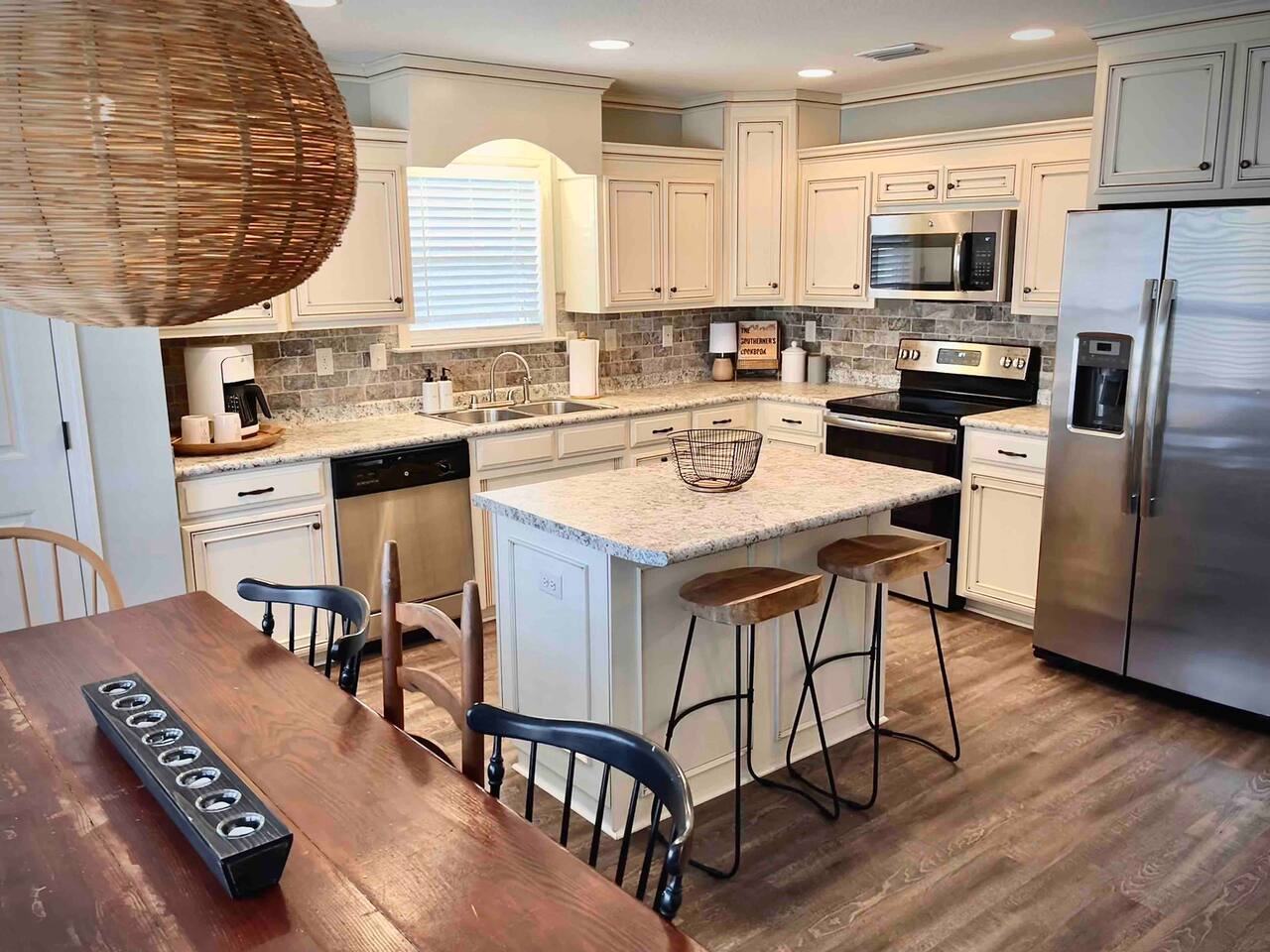 Kitchen with large granite island, bar stools and stainless appliances