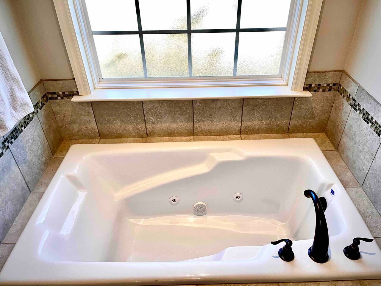 Soaker tub beneath a window in the primary bathroom