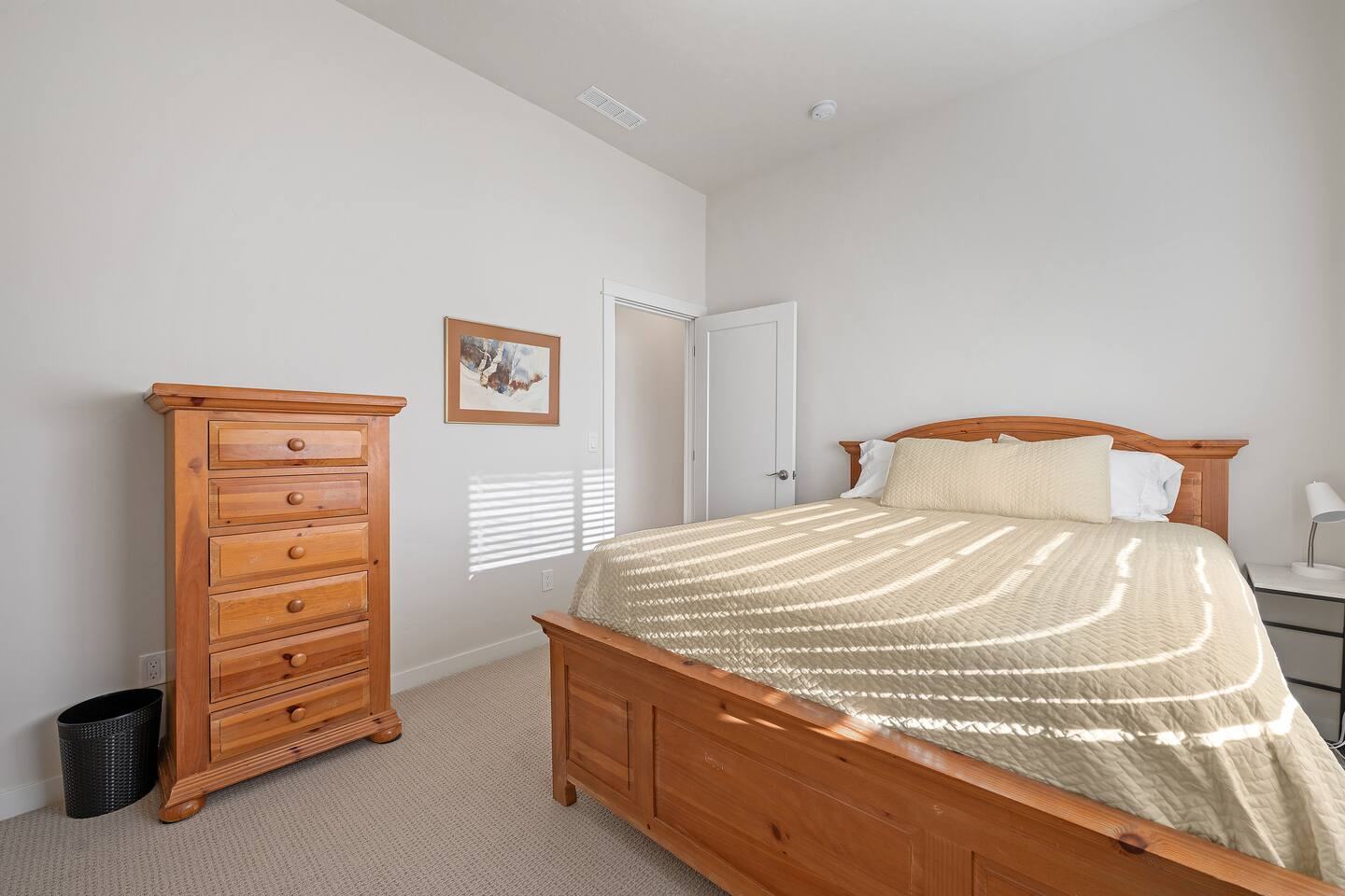 Queen bedroom with wood bed frame and tall dresser