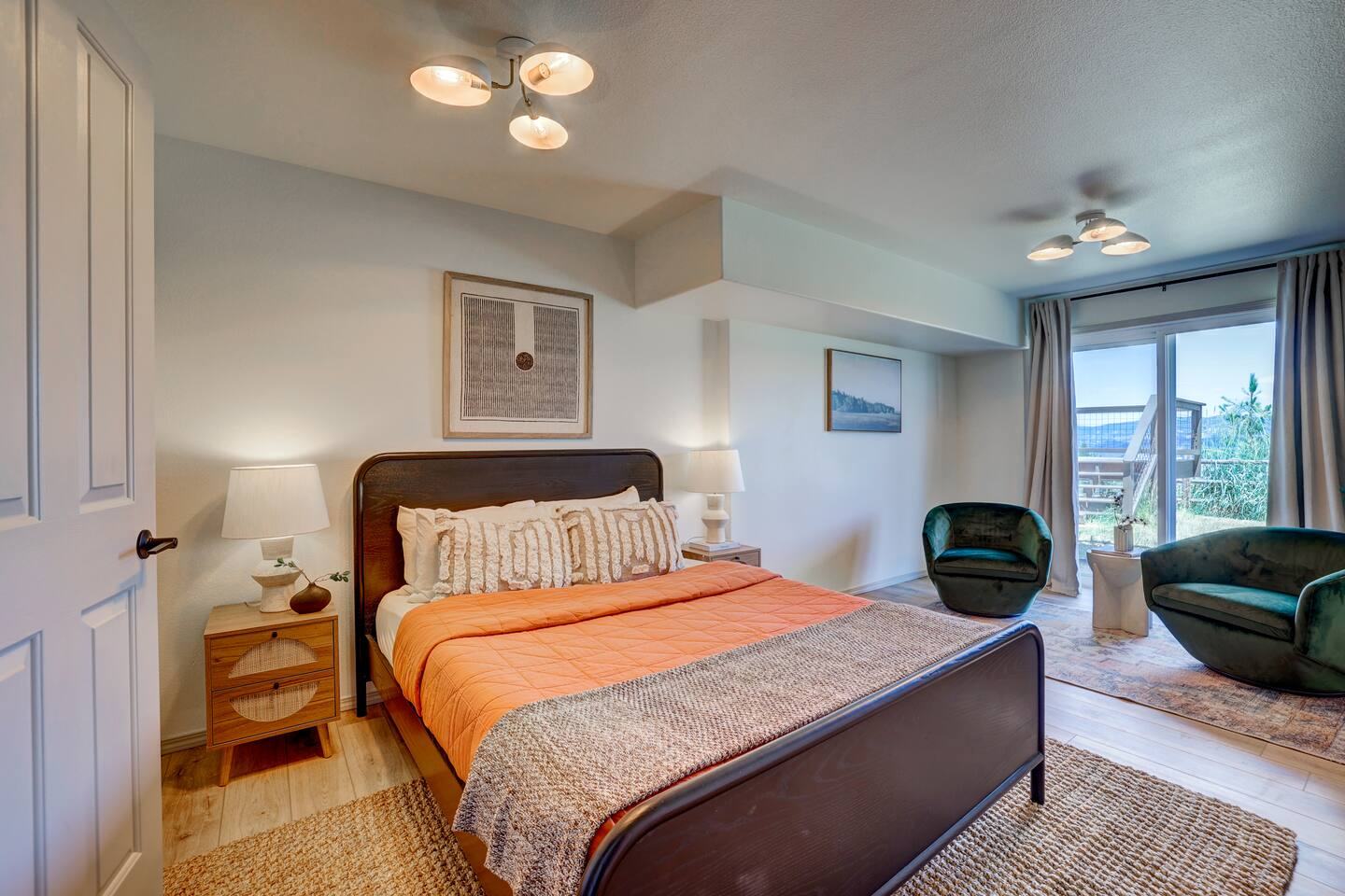 Second queen bedroom with dark wood bed and green armchairs