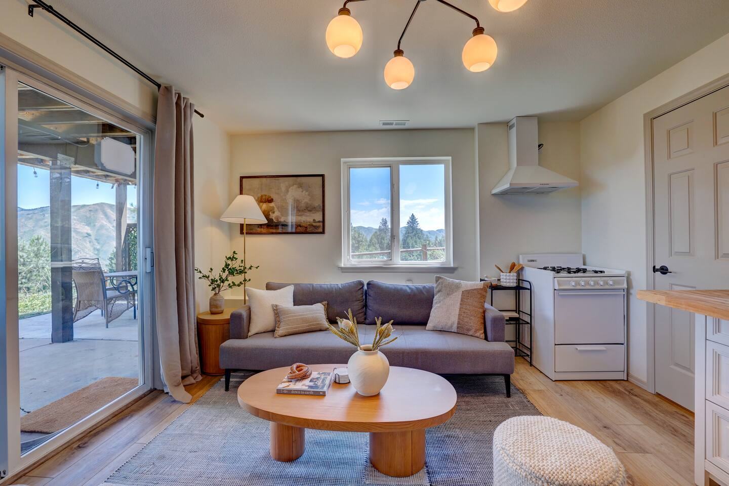 Living room with gray sofa, round wood coffee table and sliding door to the patio