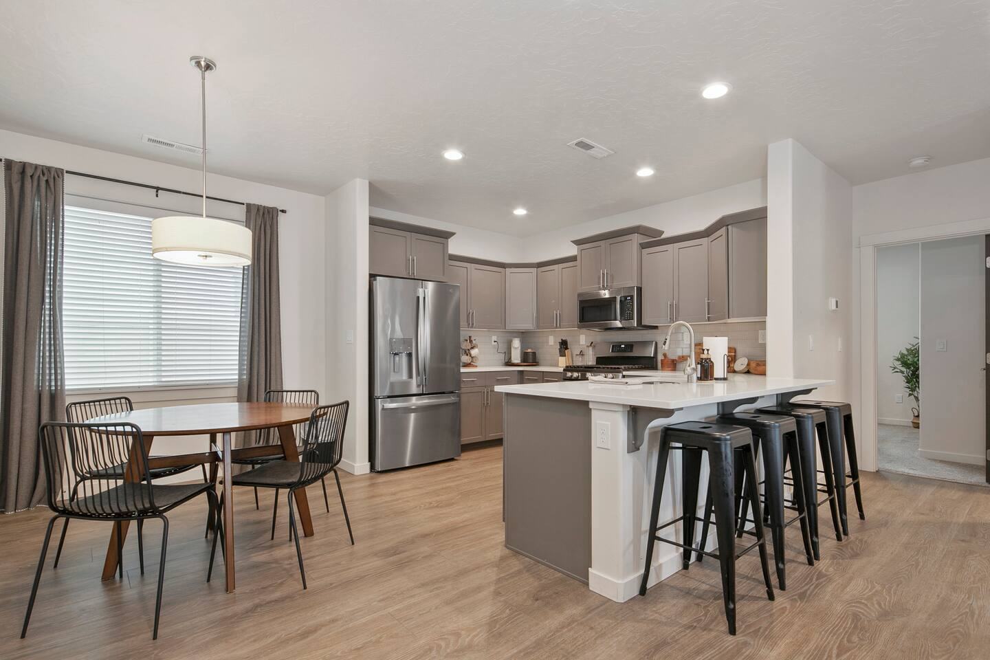Dining table and kitchen island with bar stools in the open floor plan