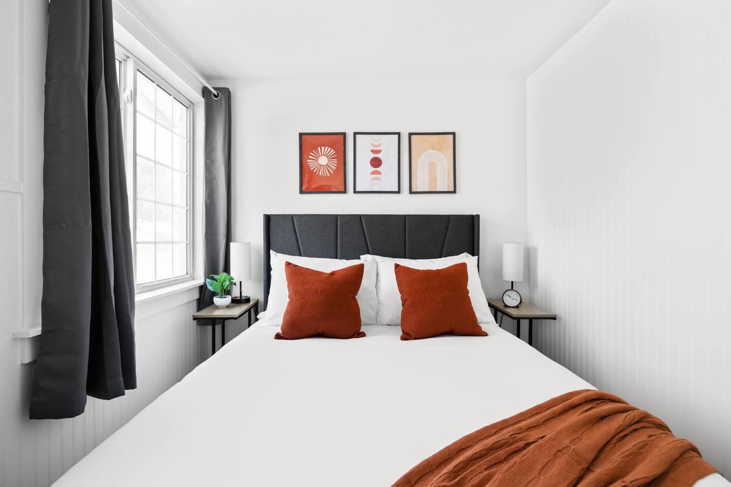 Bedroom with dark headboard, rust pillows and framed prints