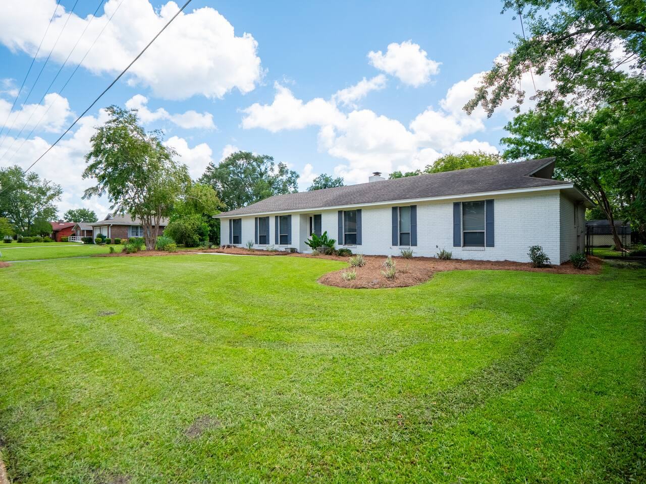 White brick ranch home with a large front lawn