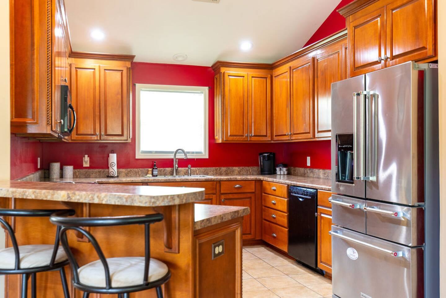 Kitchen with wood cabinets, stainless refrigerator and island with bar stools