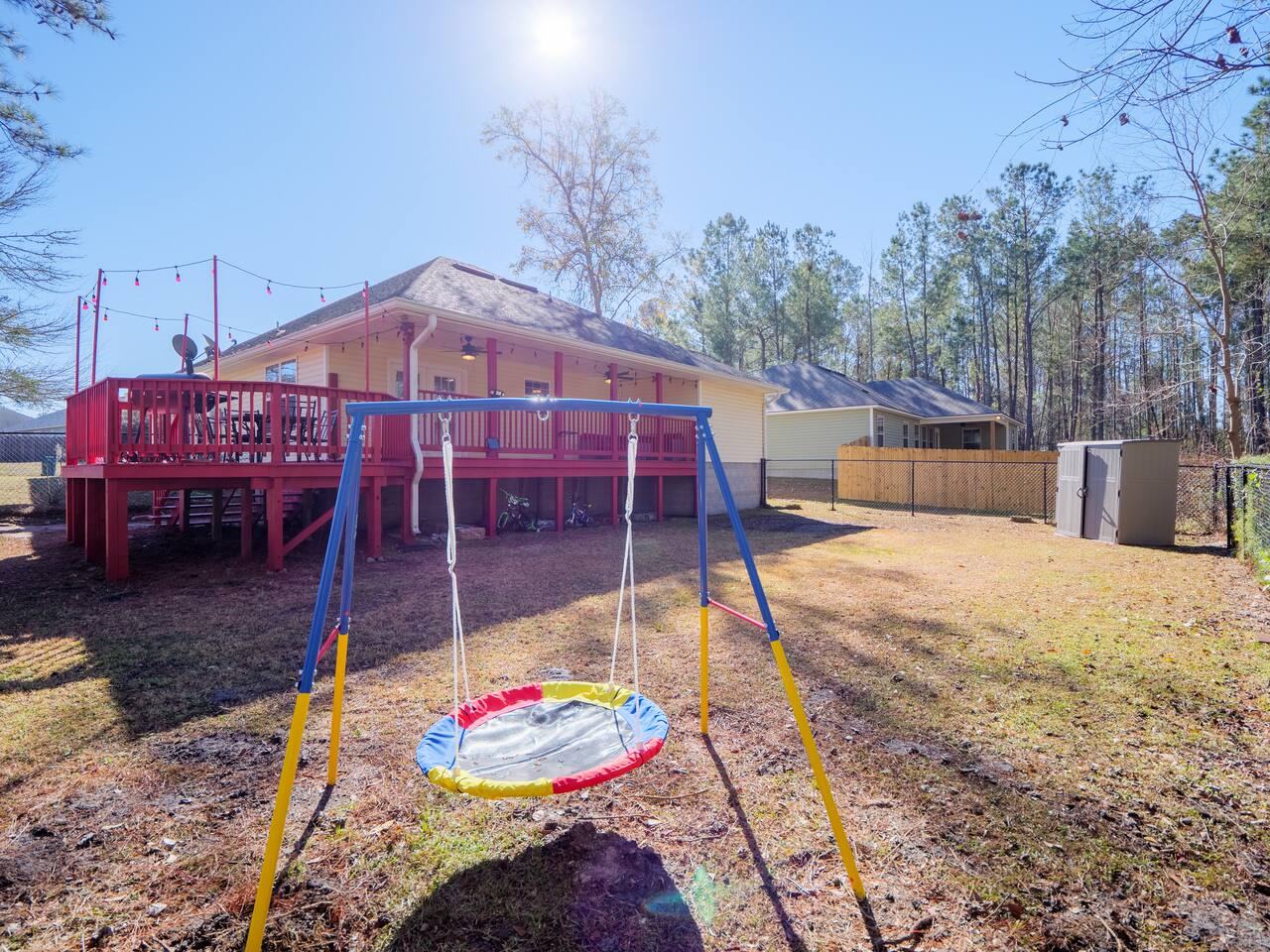 Fenced backyard with swing set and red deck