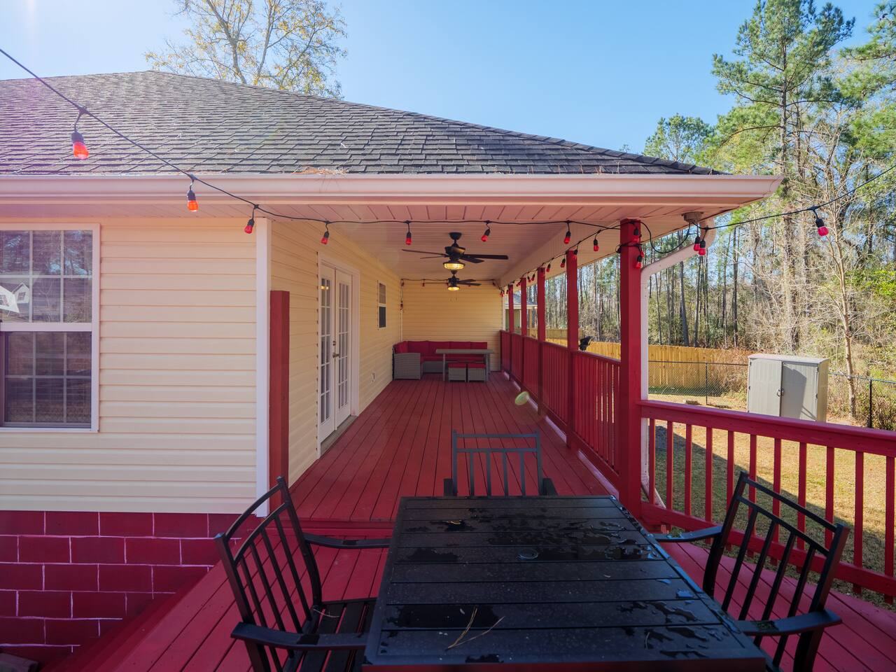Covered deck with long dining table and string lights