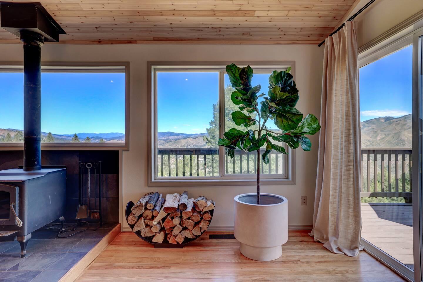 Wood stove with firewood stacked beside big view windows