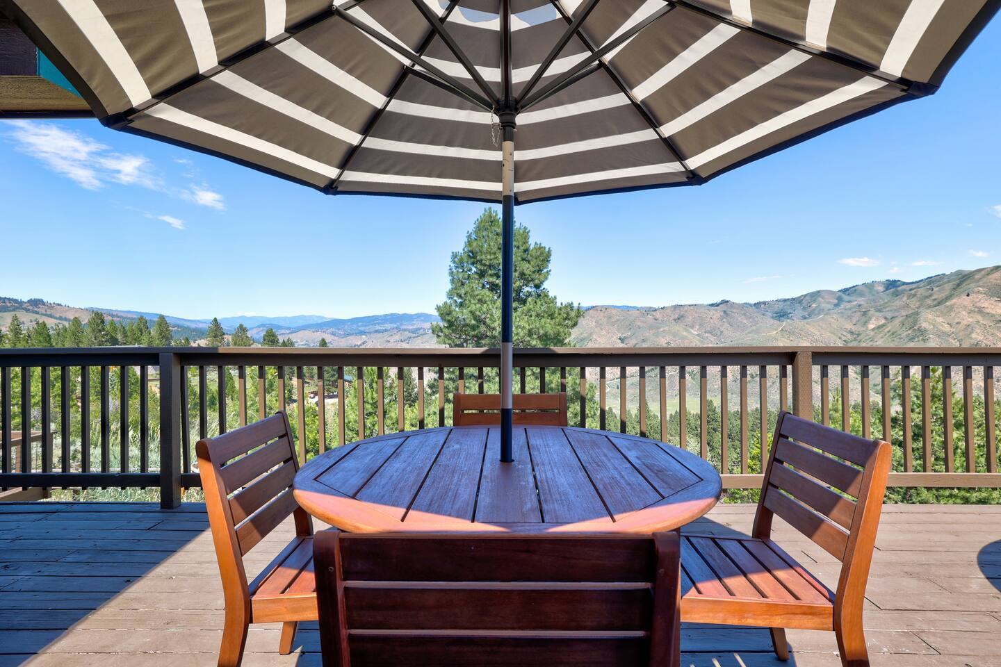 Deck dining table under an umbrella with a mountain view