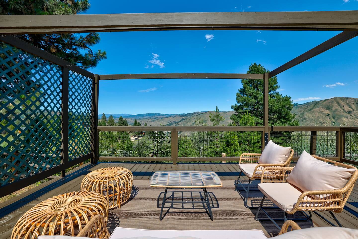 Covered deck lounge with rattan seating and a mountain view